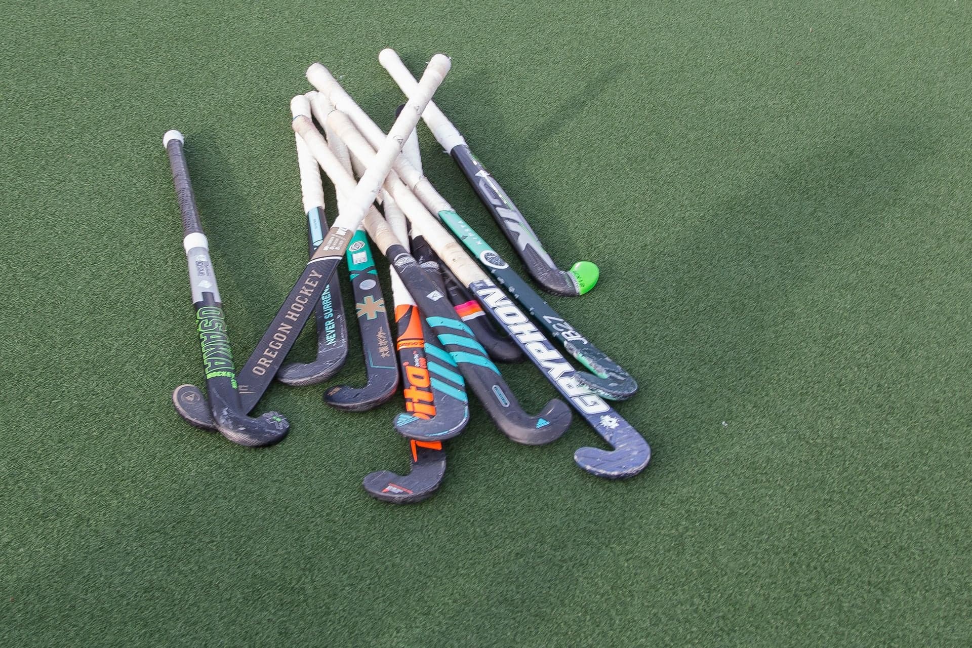 A bundle of hockey sticks laid together on an artificial pitch.